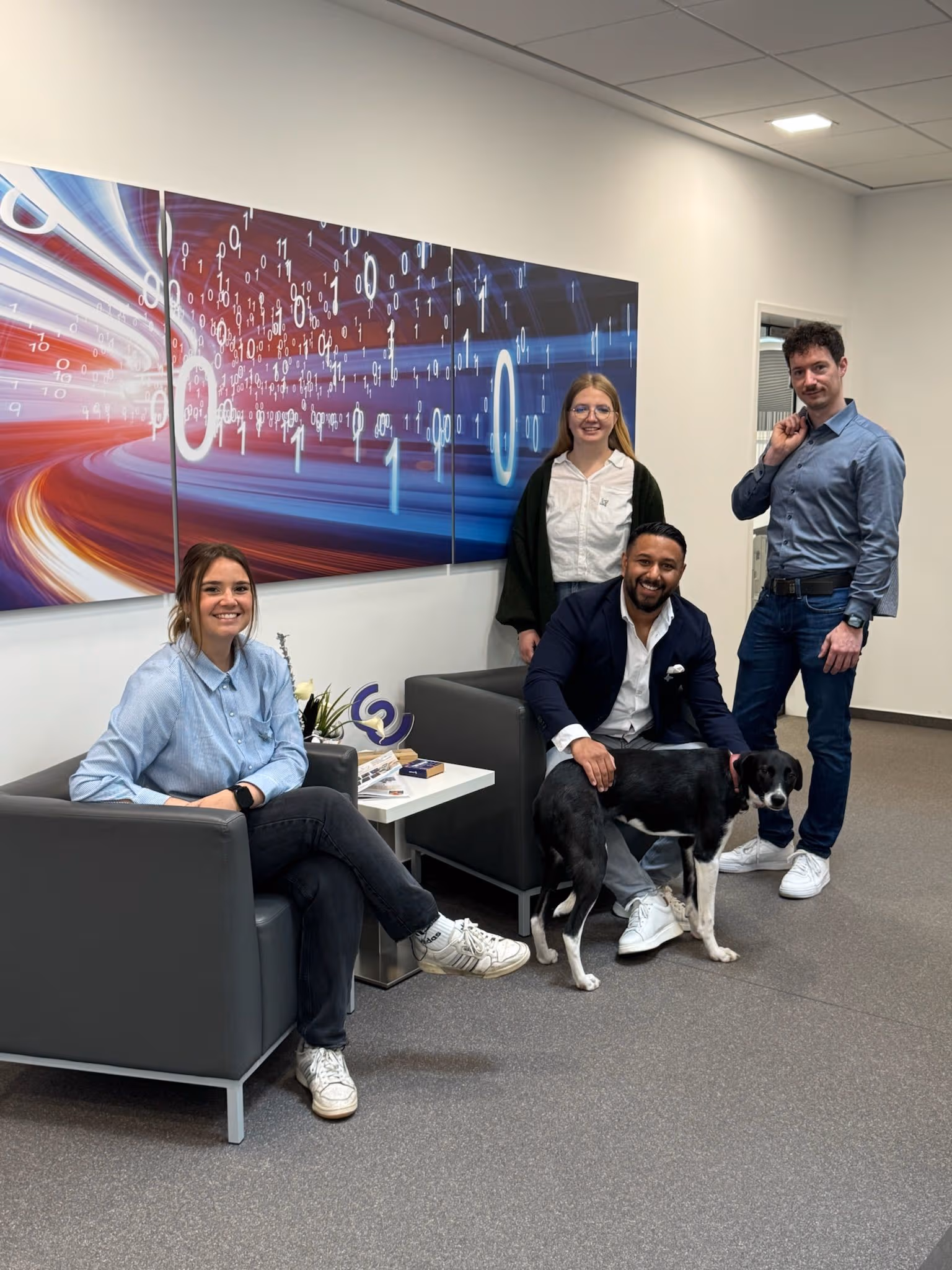 Mehrere Team-IT Mitarbeiter sitzen zusammen in einer Sitzecke im Unternehmen.