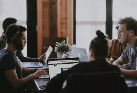 Mitarbeiter zusammen am Tisch mit Laptop bei der Arbeit
