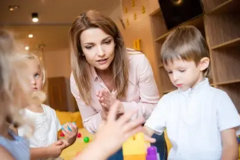 Eine Frau steht bei Kindern am Tisch