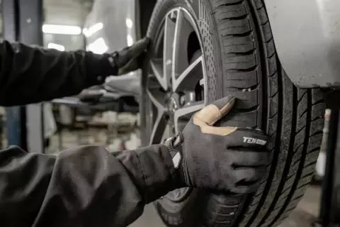 Ein Ausschnitt in einer Werkstatt wie Hände einen Autoreifen ablösen