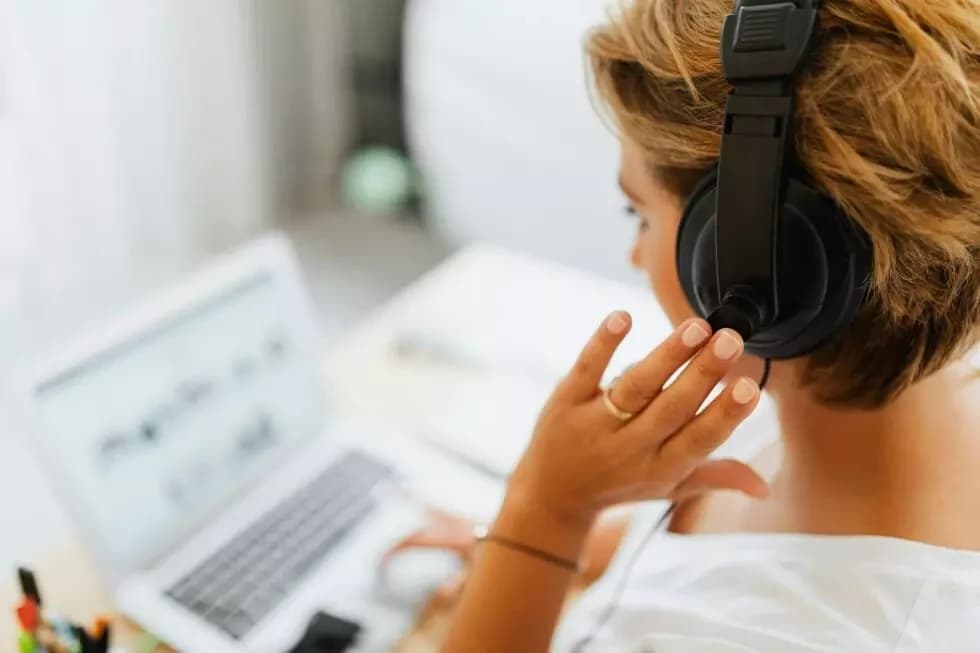 Moderne Telefonie, eine Frau hat ein Headset auf und sitzt am Monitor 